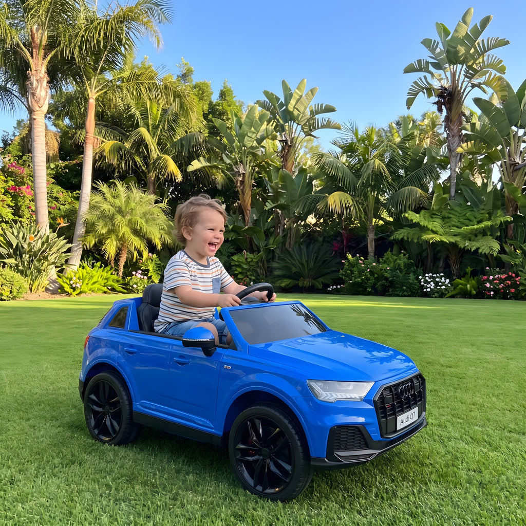Enfant au volant de l'Audi Q7 bleue électrique dans un jardin