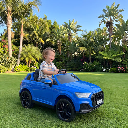 Enfant au volant de l'Audi Q7 bleue électrique dans un jardin