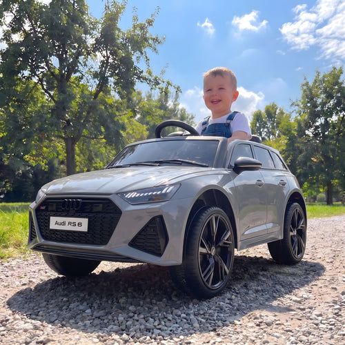 Enfant au volant de l'Audi RS6 électrique grise sur un chemin