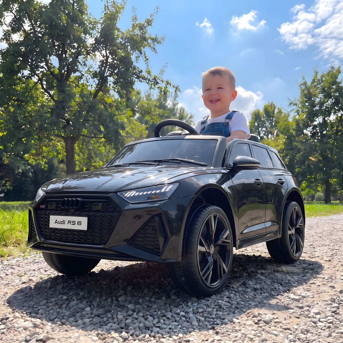 Enfant au volant de l'Audi RS6 électrique noire dans un parc