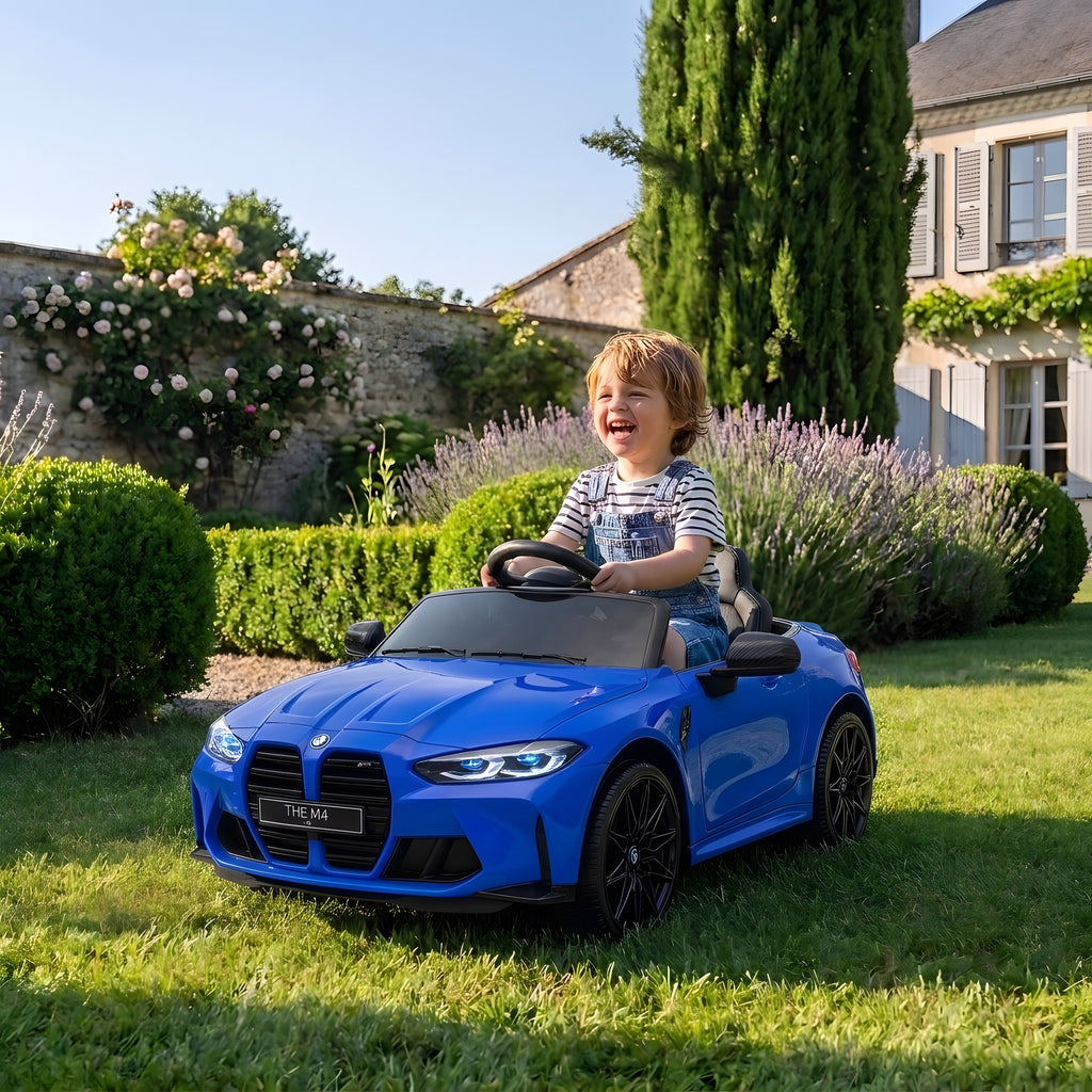 Enfant au volant de la BMW M4 bleue électrique dans un jardin