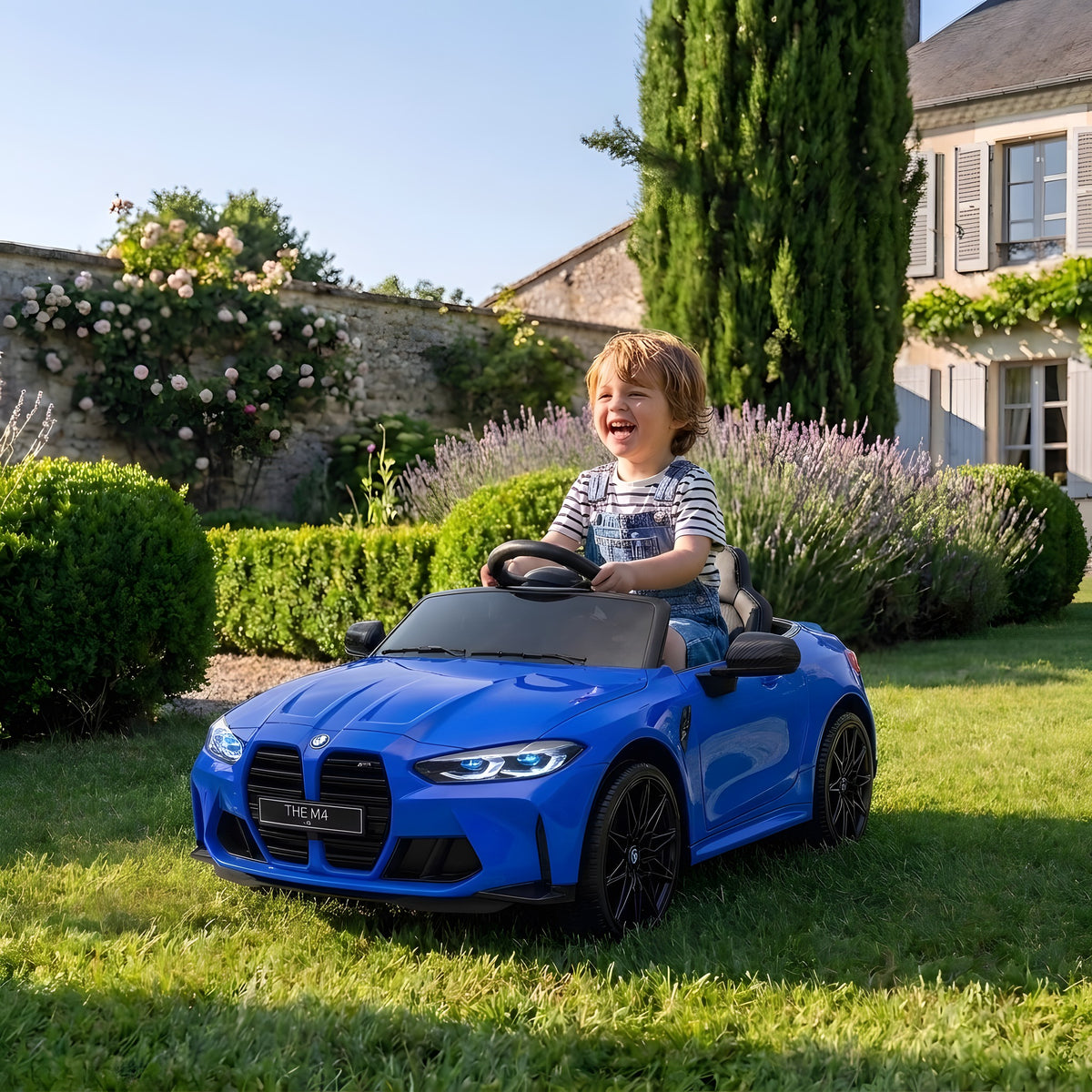 Enfant au volant de la BMW M4 bleue électrique dans un jardin