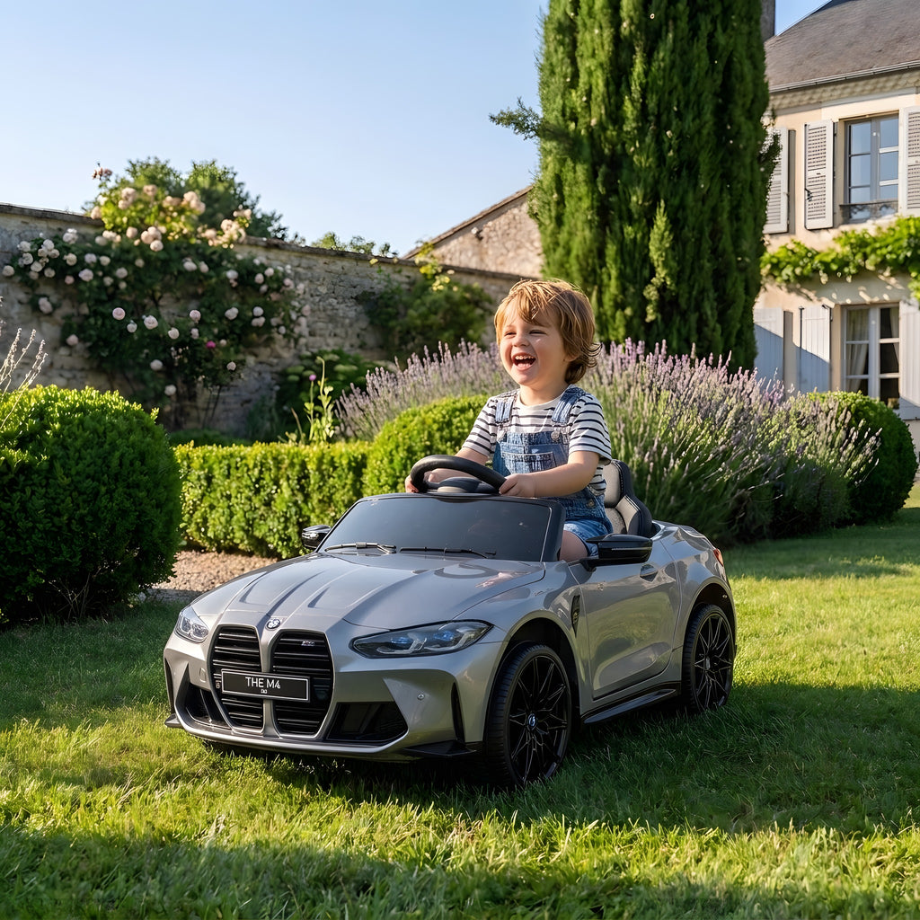 Enfant au volant de la BMW M4 grise électrique dans un jardin