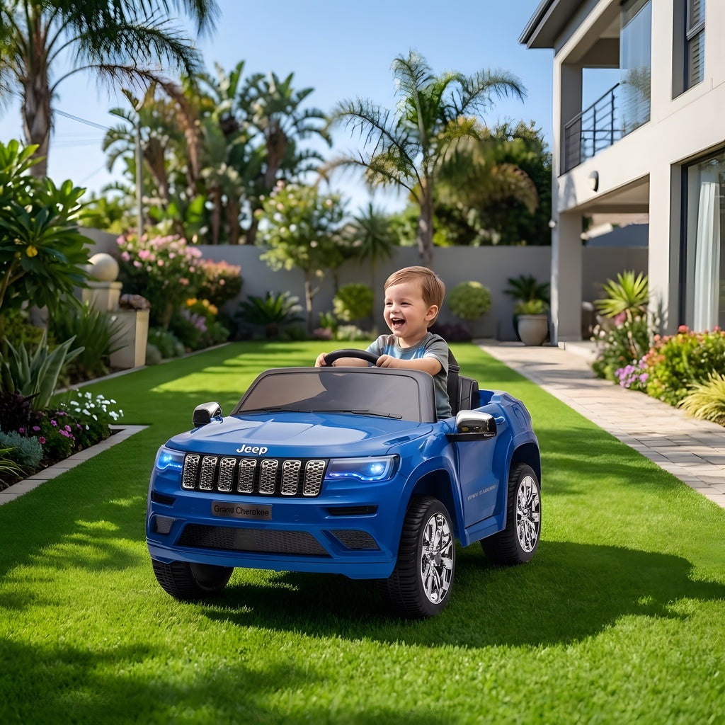 Enfant au volant de la Jeep Grand Cherokee bleue électrique dans un jardin