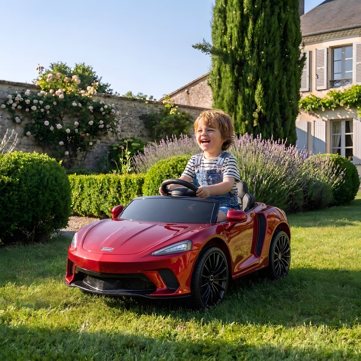 Enfant au volant de la McLaren 620 GT électrique dans un jardin