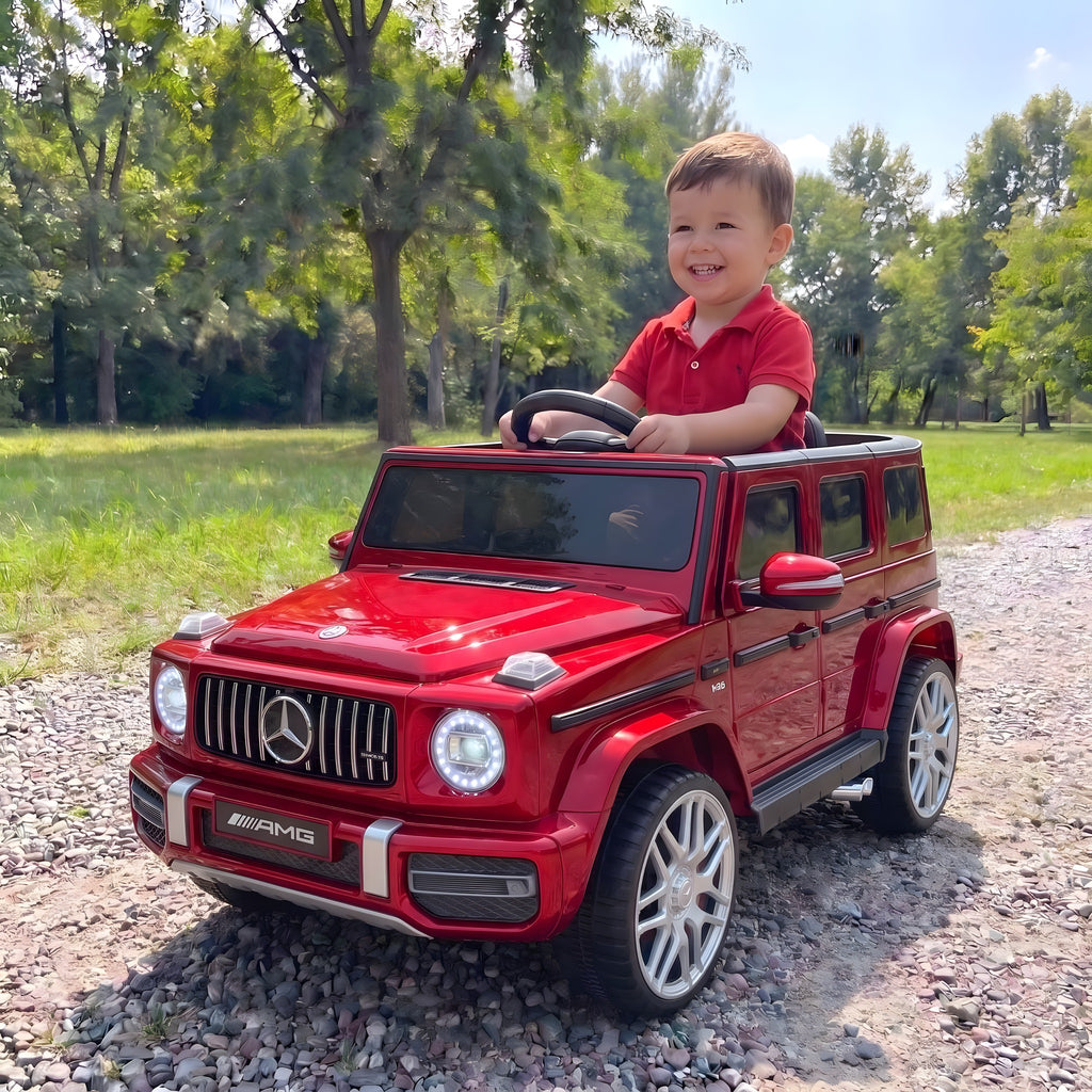 Enfant au volant du Mercedes G63 rouge électrique dans un parc