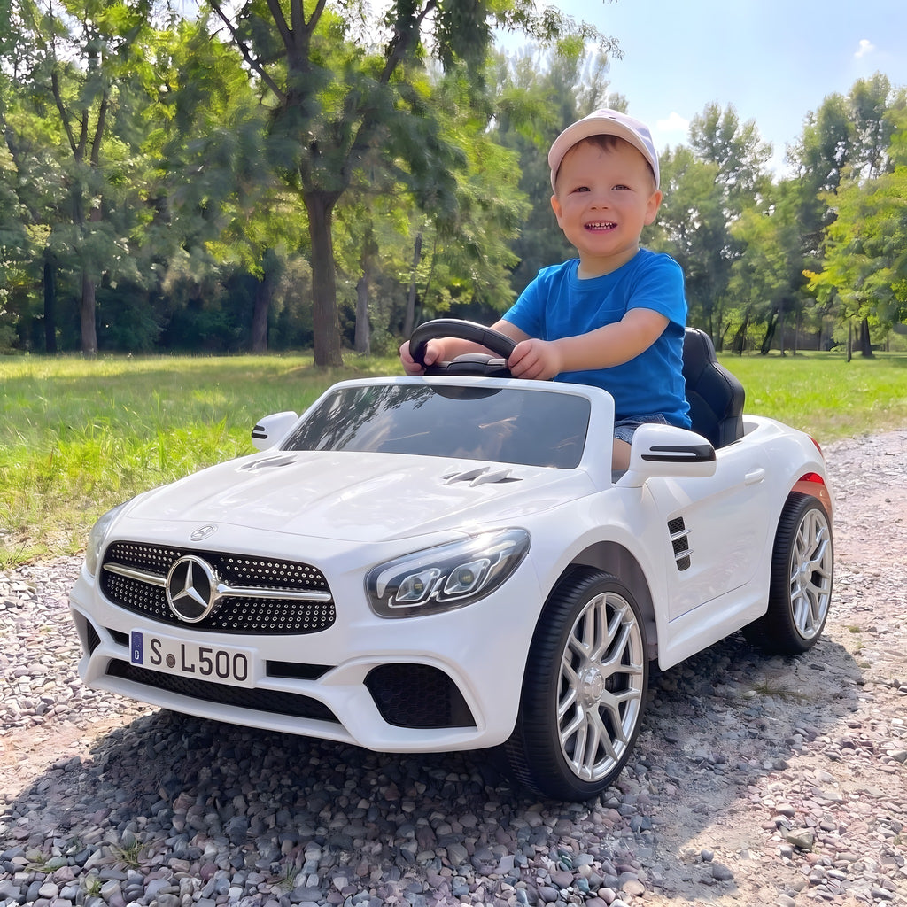 Enfant au volant de la Mercedes SL500 blanche électrique dans un parc