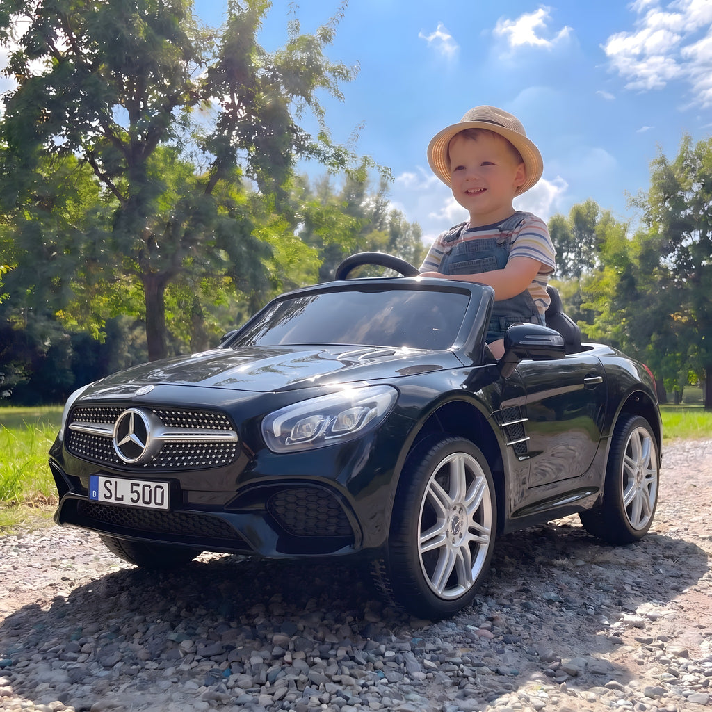 Enfant au volant de la Mercedes SL500 noire électrique dans un parc
