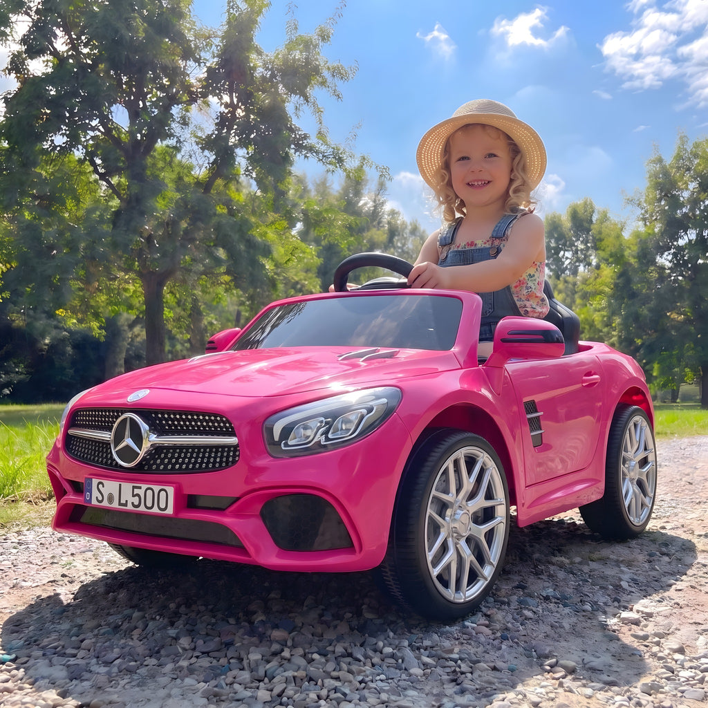 Enfant au volant de la Mercedes SL500 rose électrique dans un parc