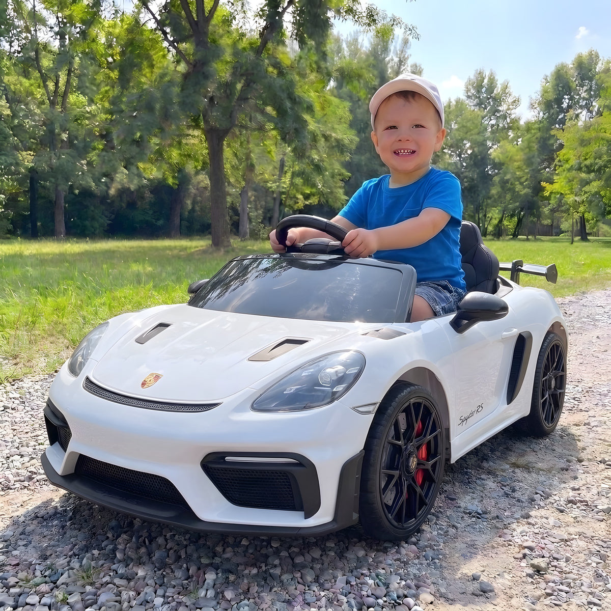 Enfant au volant de la Porsche Spyder RS blanche électrique dans un parc