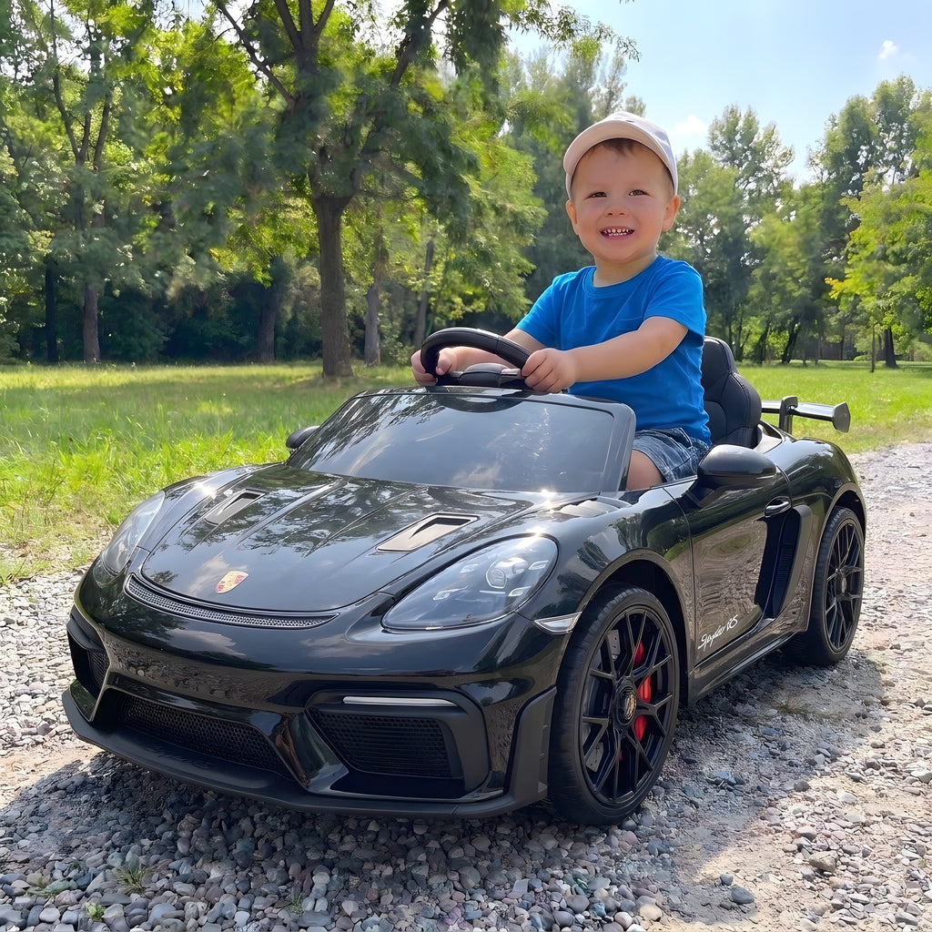 Enfant au volant de la Porsche Spyder RS noire électrique dans un parc