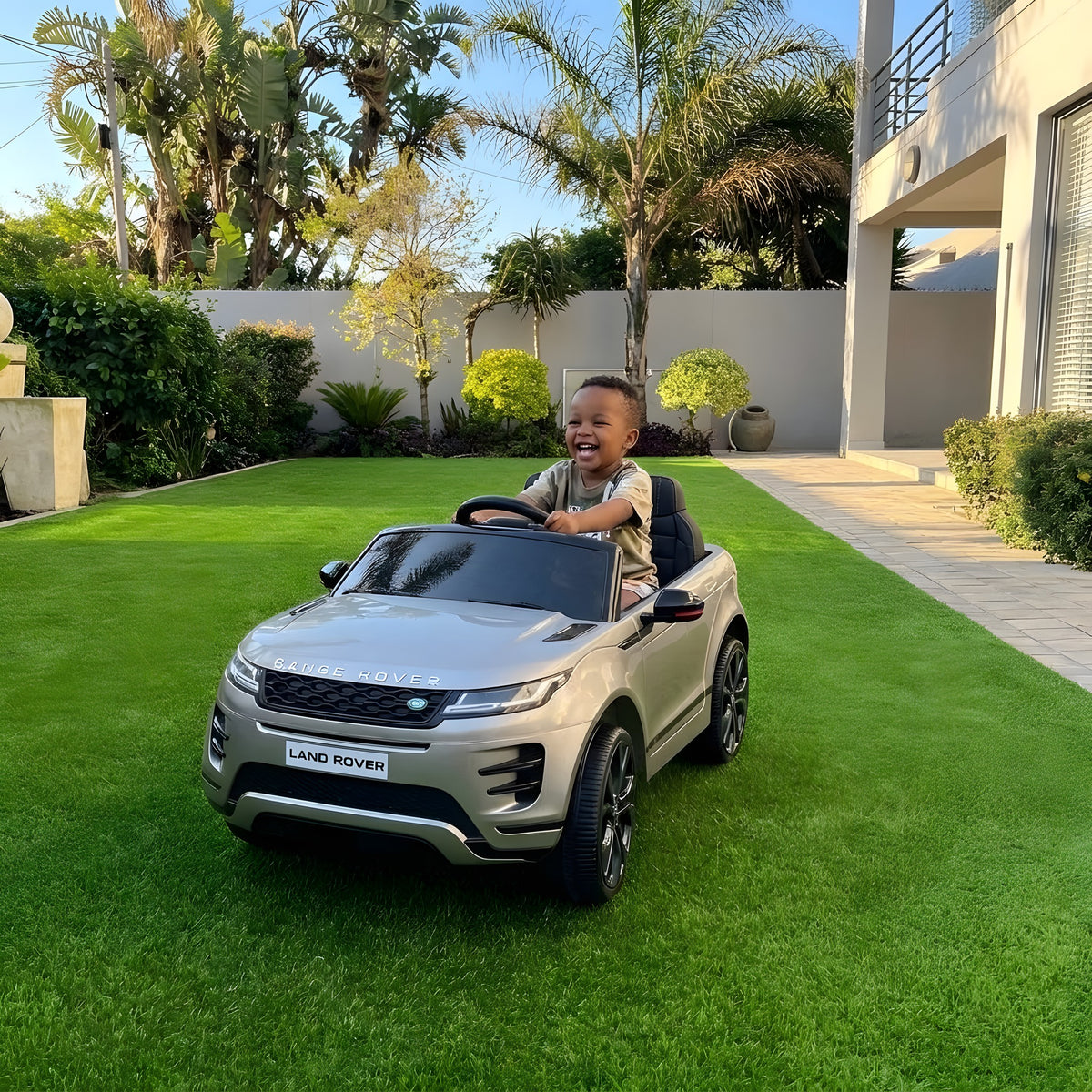 Enfant au volant du Range Rover Evoque gris électrique dans un jardin
